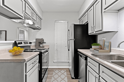 a kitchen with white cabinets and a black refrigerator