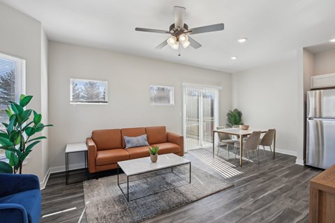 A living room with a brown couch and a ceiling fan.