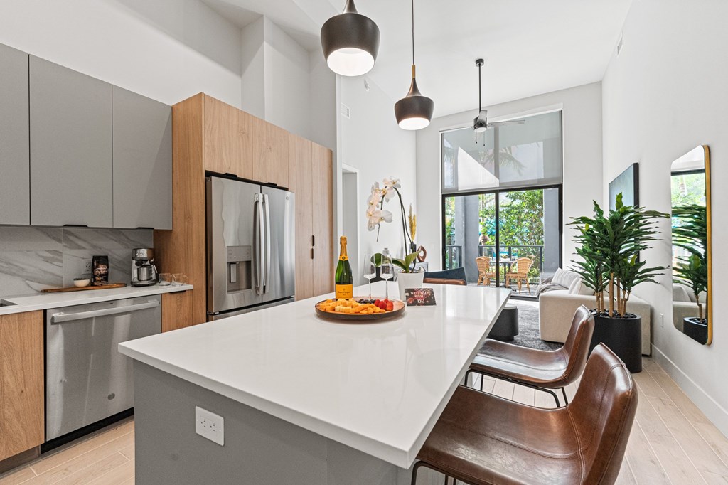 A modern kitchen with a white island and brown chairs.