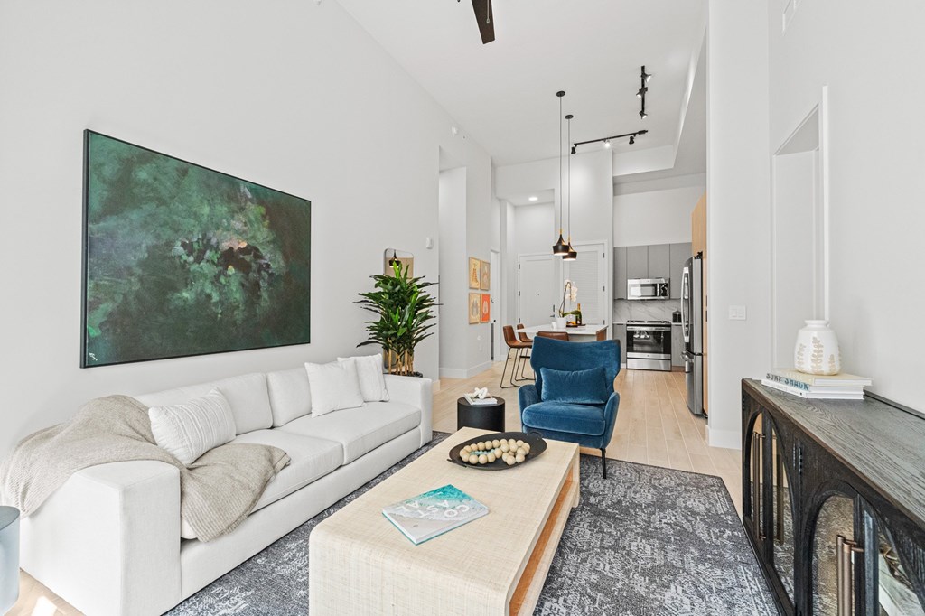 A living room with a white couch and a painting on the wall.