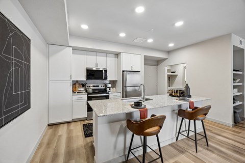 A modern kitchen with white cabinets and a bar area.