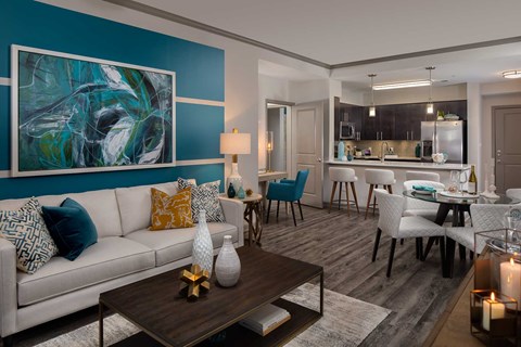 A modern living room with a white sofa and a large abstract painting on the wall.
