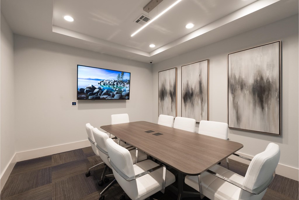 a conference room with a table and chairs and a television on the wall