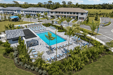 A swimming pool surrounded by trees and a building in the background.