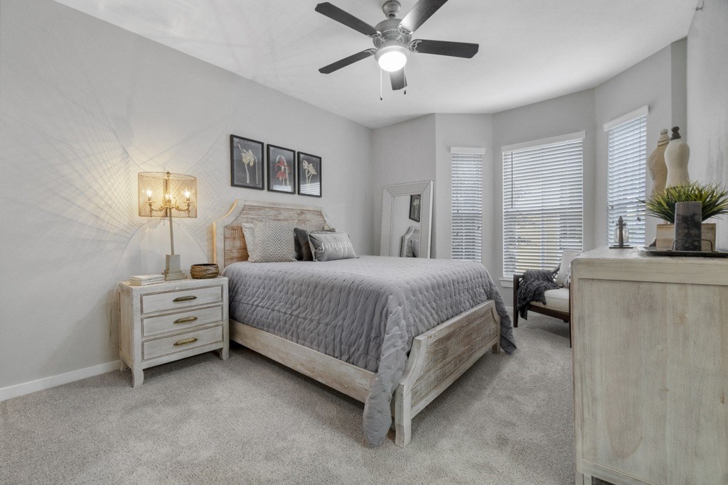 Bedroom with ceiling fan, large bay window, and carpet