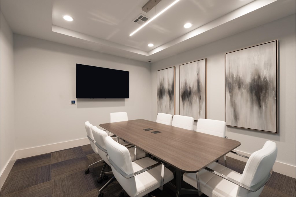 a conference room with a long wooden table and white chairs
