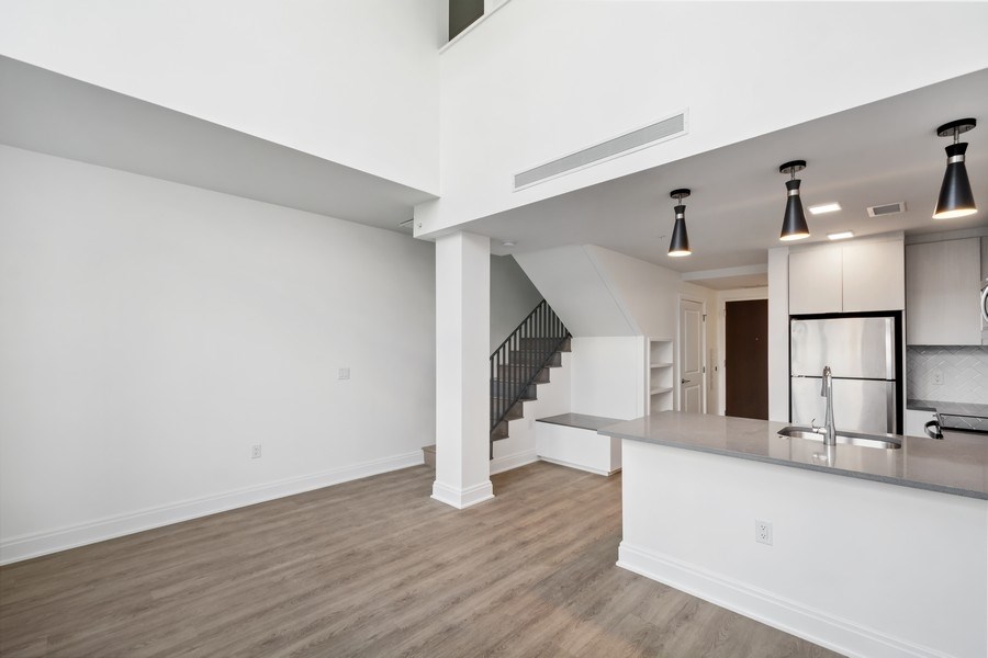 the living room and kitchen of a new home with white walls and wood flooring