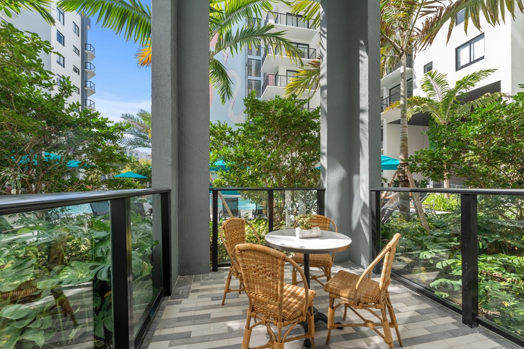 A patio with a table and chairs overlooks a lush green garden.