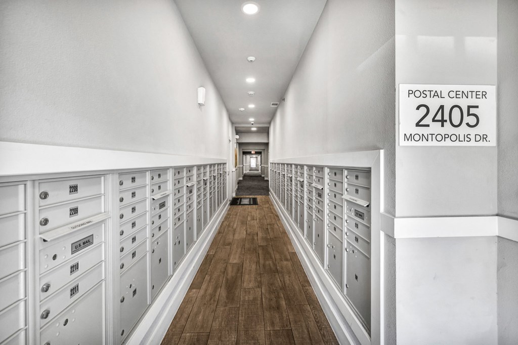 a long hallway with white cabinets and a sign that reads postal center 2400 montours