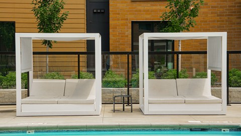 Two white couches are placed on either side of a pool.
