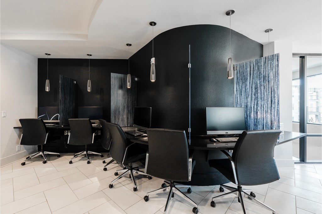 a conference room with black chairs and a desk with a computer