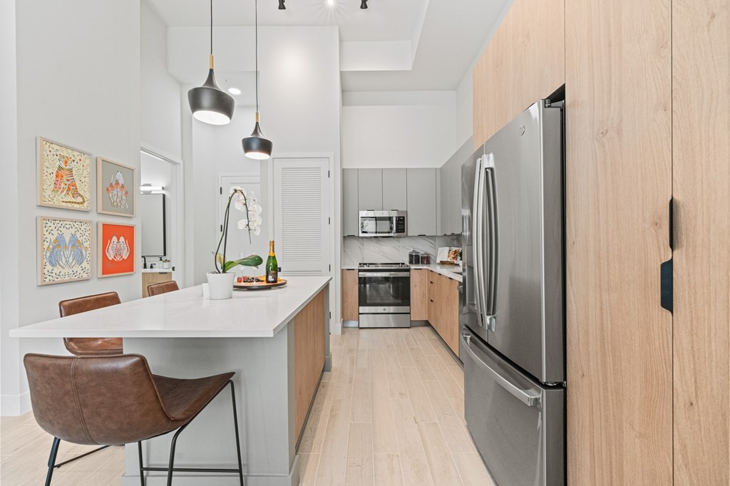 A modern kitchen with a white island and a refrigerator.