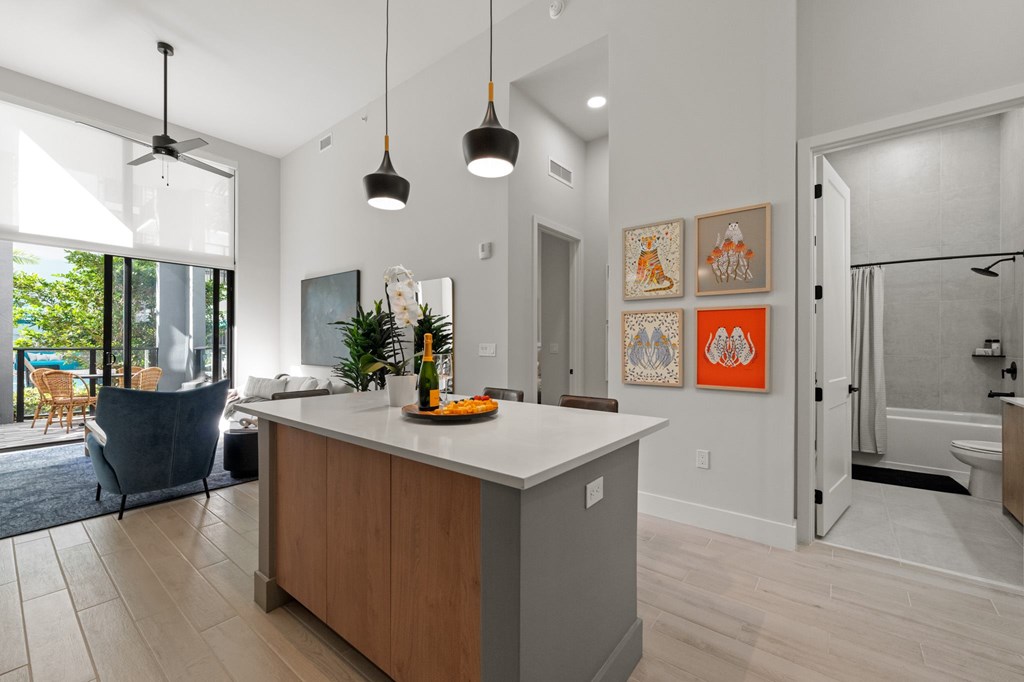 A kitchen with a white counter top and a grey island.