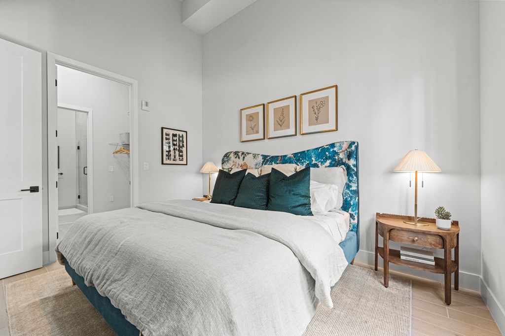 A bedroom with a bed, nightstand, and pictures on the wall.