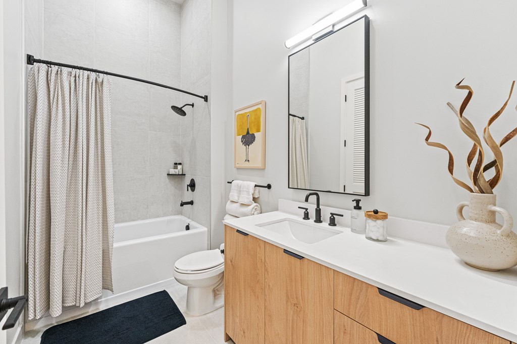 A bathroom with a white toilet, a sink, a mirror, and a shower curtain.