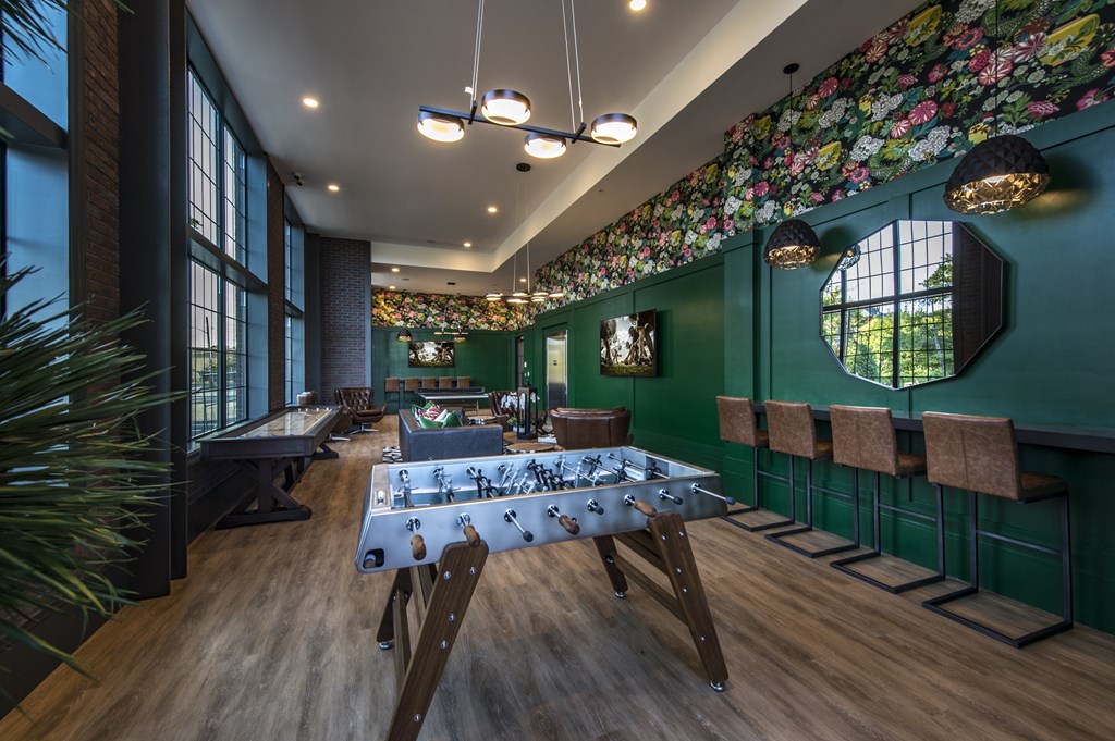 A room with a foosball table and a long green wall.