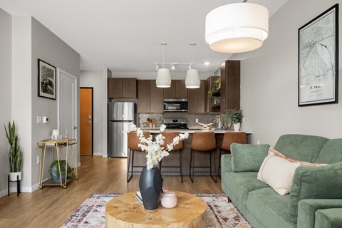 A modern living room with a green couch and a coffee table with a vase of flowers on it.
