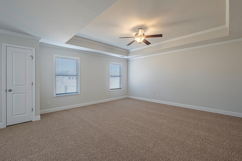 an empty living room with a ceiling fan and a door