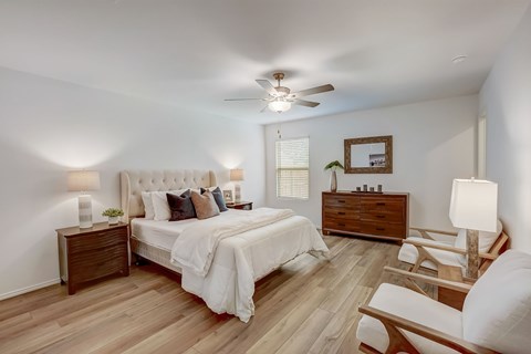 Large rustic bedroom, with light hardwood floors and naturally lit through windows on each wall