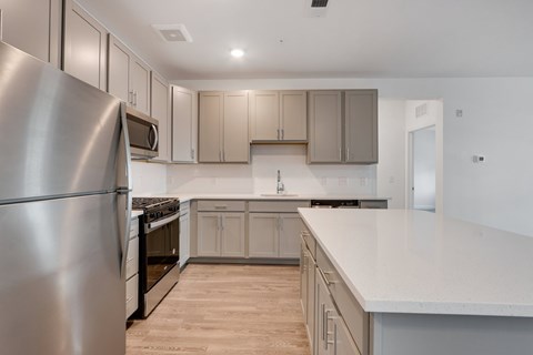 A modern kitchen with a stainless steel refrigerator and wooden flooring.