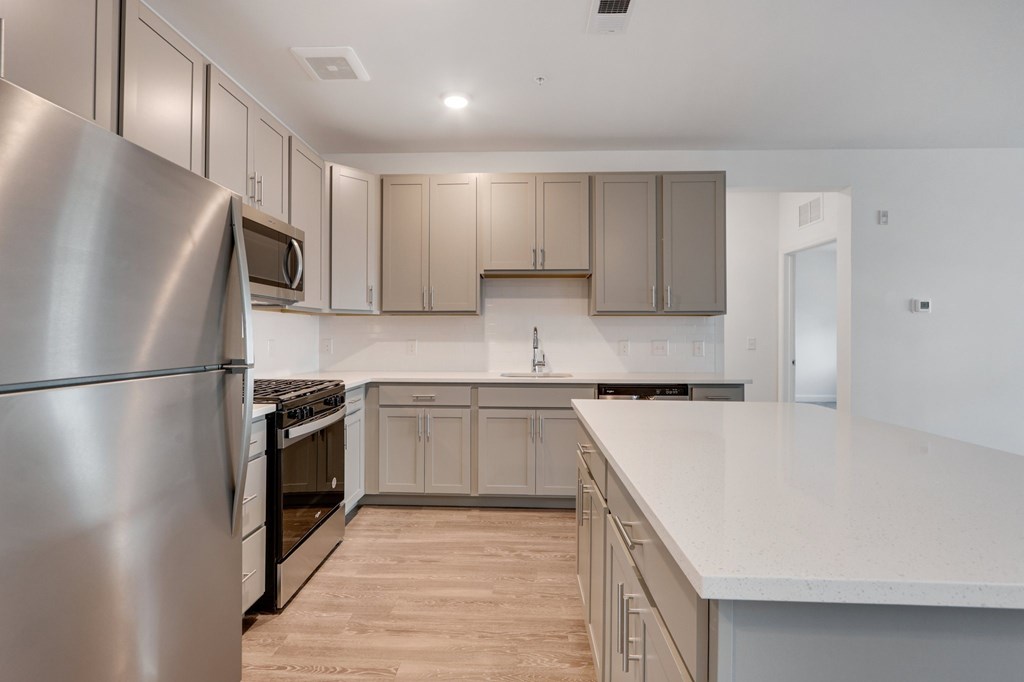 A modern kitchen with a stainless steel refrigerator and wooden flooring.