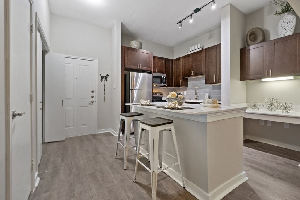 Kitchen with stainless steel appliances and custom espresso cabinetry, kitchen island, built-in desk, and marble countertops
