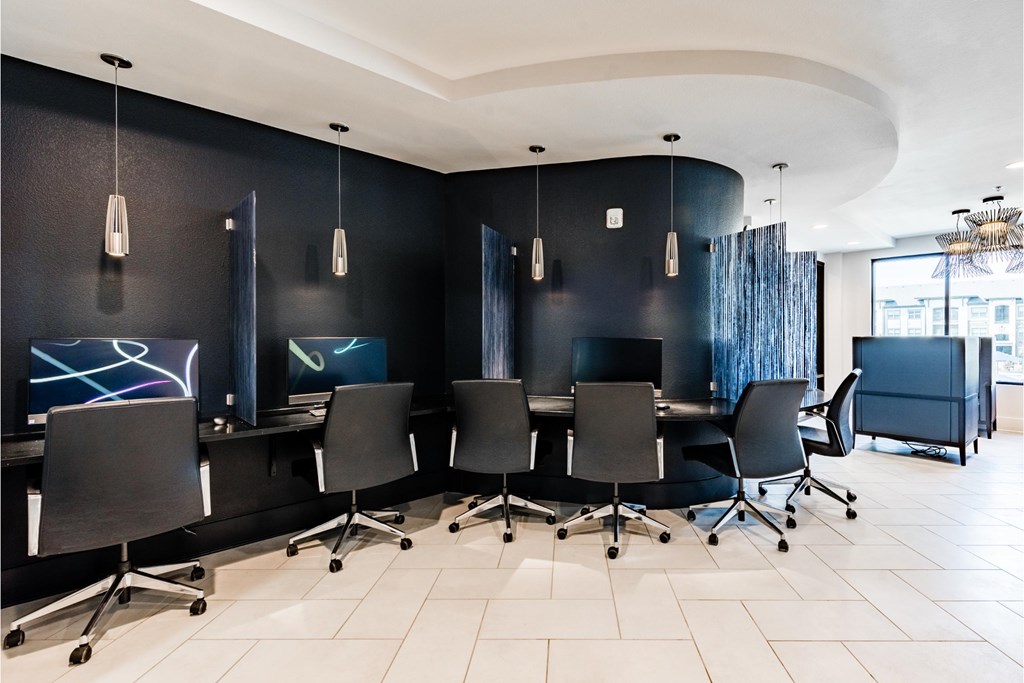a conference room with black chairs and a table with monitors
