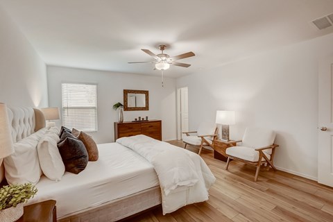 Generous and cozy bedroom adorned with hardwood floors, basking in the comfort of natural light