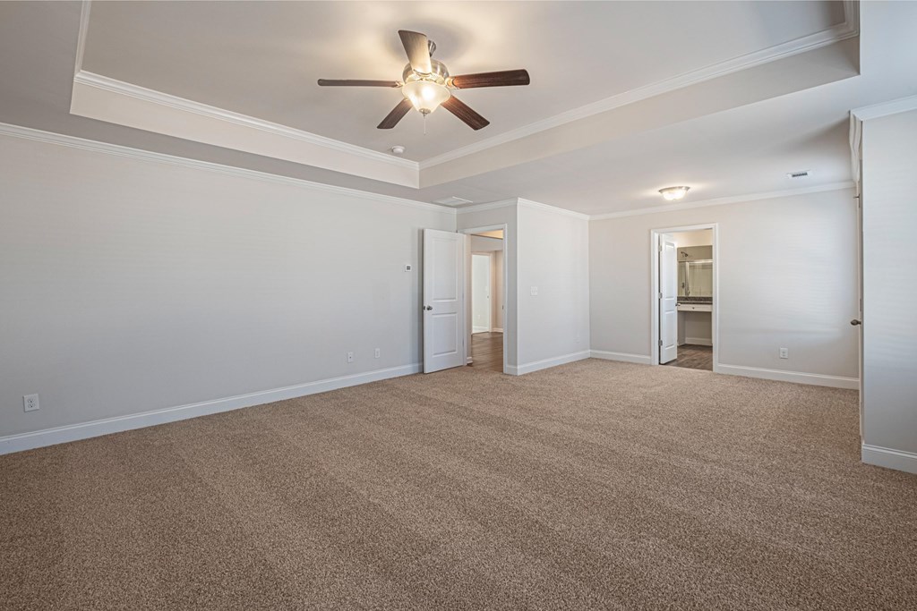 an empty living room with a ceiling fan and a carpet