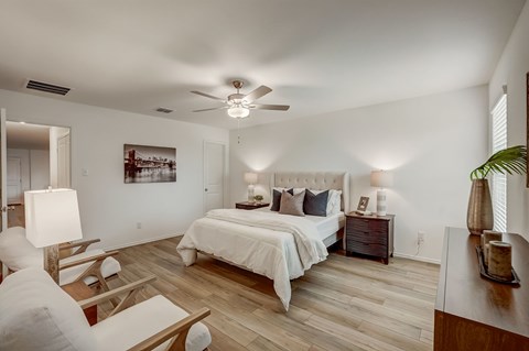 Large rustic bedroom, with light hardwood floors and naturally lit through windows on each wall
