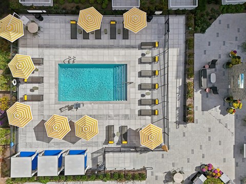 An aerial view of a pool surrounded by yellow umbrellas and lounge chairs.