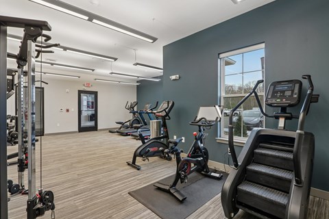A gym with a variety of exercise equipment including treadmills, stationary bikes, and weight machines.