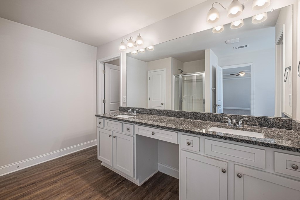 a bathroom with white cabinets and granite counter tops and a large mirror