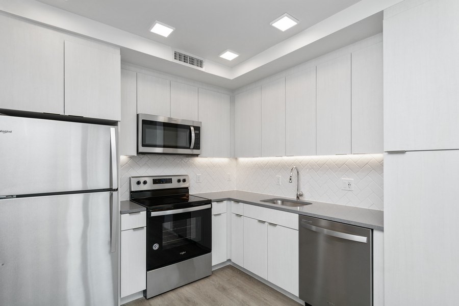 a kitchen with white cabinets and stainless steel appliances