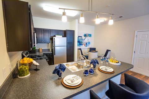 A kitchen with a table set for two with blue napkins.