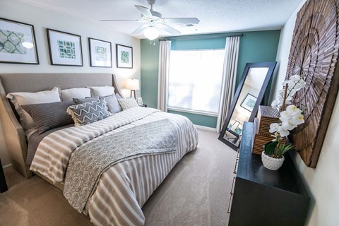 A bedroom with a large bed and a ceiling fan.