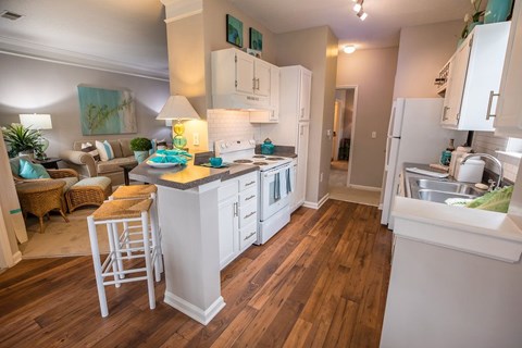 A kitchen with white cabinets and a wooden floor.