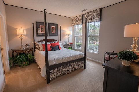 A bedroom with a four poster bed and a window with blinds.