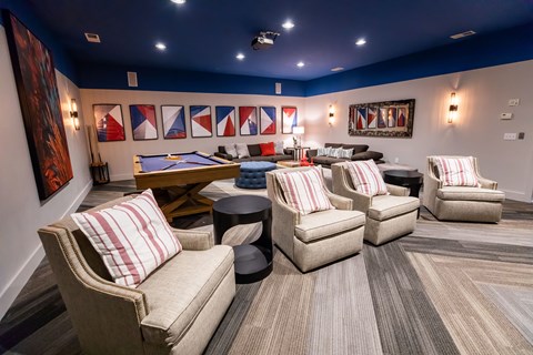 A room with a pool table and several chairs.