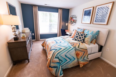 A bedroom with a bed, nightstand, and window.