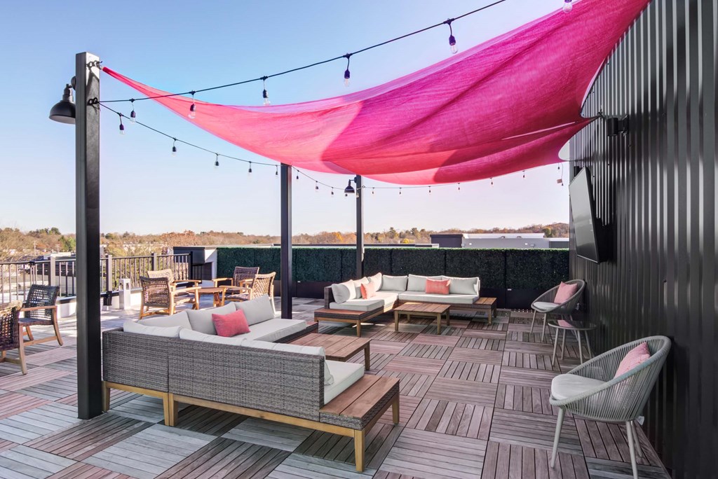 A patio with a couch, chairs, and a pink canopy.