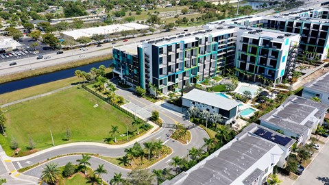 A view of a green field and apartment buildings from above.