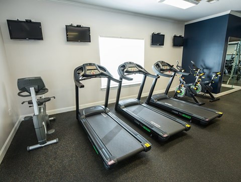 A gym with treadmills, elliptical machines, and a stationary bike.