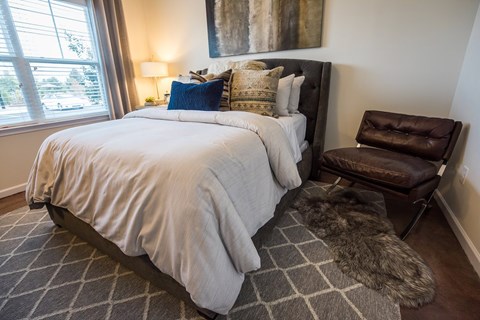 A bedroom with a large bed and a brown leather chair.