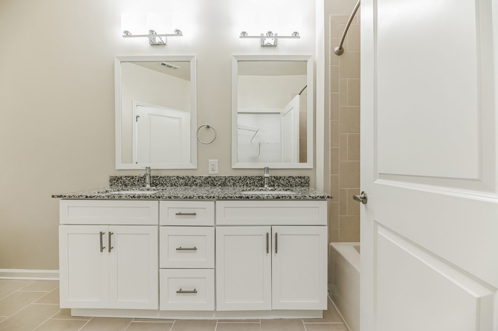 a bathroom with white cabinets and a sink and mirror