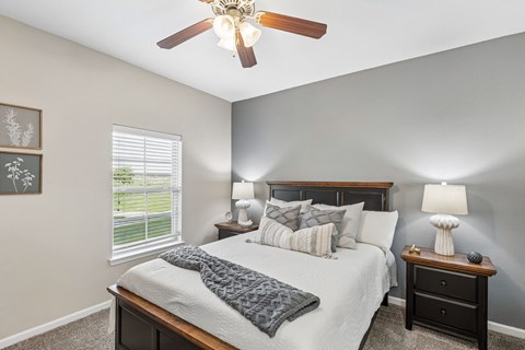 A bedroom with a bed, nightstand, and a ceiling fan.