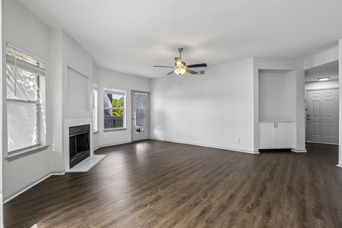 A spacious room with a fireplace and wood flooring.