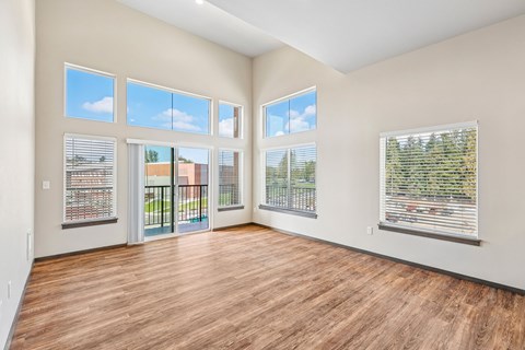A room with wooden floors and large windows overlooking a street.