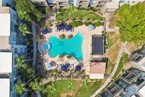 An aerial view of a swimming pool surrounded by buildings and trees.