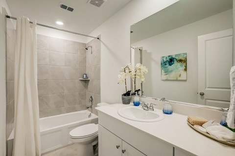 Bathroom featuring a relaxing garden tub, complemented by a sizable mirror and white cabinets